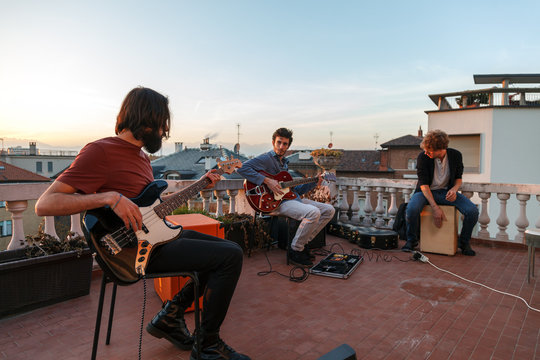 young people playing music together on a terrrace on a rooftop at sunset