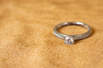 Jewelry diamond ring on golden fabric background close up