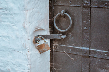 The lock hanging on an old black metal door