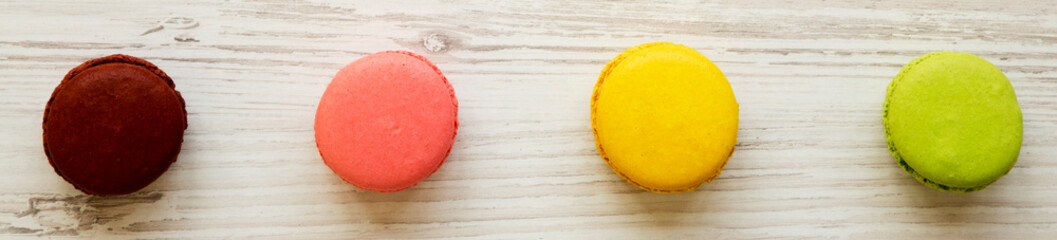 Colorful macaroons on a white wooden background, overhead view. Flat lay, from above, top view.