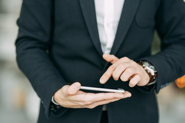 The phone on the hand of a business man, with his hand and finger touches. Blank for designers with bokeh.