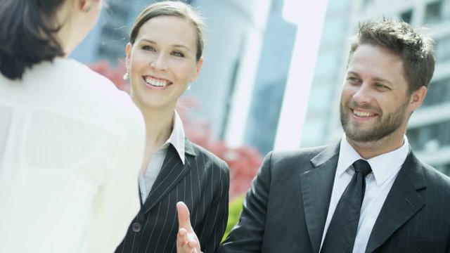 Handshake between male and female multi ethnic business colleagues meeting outside downtown office building 