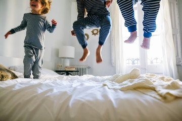 Kids wearing pajama jumping on bed. 