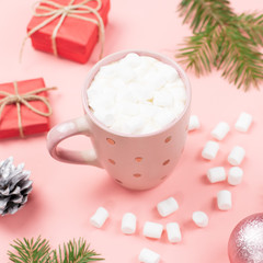 Hot drink with marshmallows close up. Christmas background with fir branches, lights, presents, pink decorations on pink