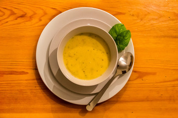 Homemade cream of potato soup with carrot and onion served in a bowl on wooden table background, top view. Free space for text.