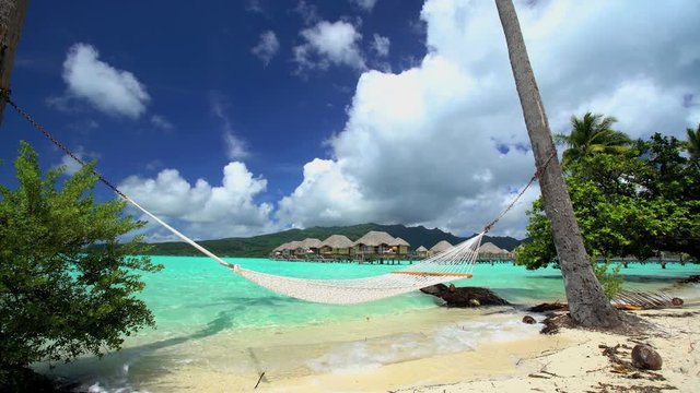 Beach hammock Overwater Bungalows in tropical aquamarine lagoon a luxury vacation resort in Bora Bora South Pacific French Polynesia
