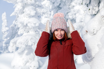 A girl in a pink knitted hat with a pompon and white mittens with a pattern in a warm jacket of...