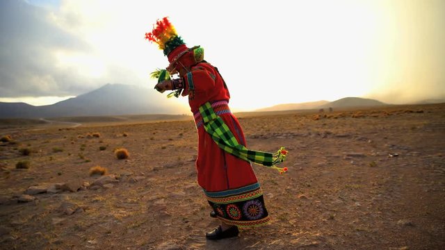 Proud Latin American Indigenous women dancing in traditional National Headdress and costume at sunset Bolivian desert South America