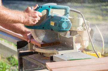 Man doing home renovations cutting wood with a saw
