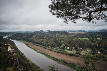 Deadpan dark misty fog mountains from viewpoint of Bastei in Saxon Switzerland, Germany to the mountains at sunrise in the morning fog, National park Saxon Switzerland