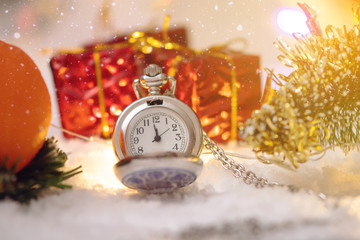 Pocket watch with a dial in the snow with gifts on the eve of holidays. Waiting for the magic of...
