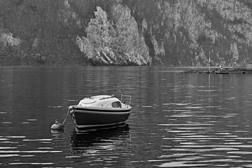 Vintage black and white view over calm and peaceful Austrian alps lake. Lonely boat or yacht at the lake near Hallstatt Salzkammergut Austria