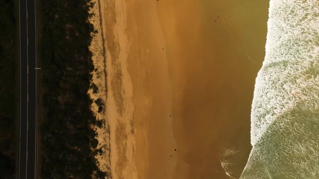 Low tide waves from a beach creeping up to a road on a coastline