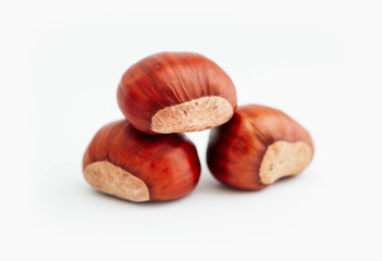 Three roasted chestnuts in a pile, isolated on white background.