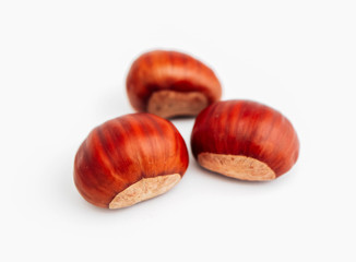 Three roasted chestnuts, close up, isolated on white background.