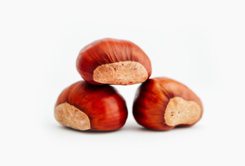 Three roasted chestnuts in a pile, isolated on white background.