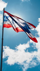 Thai flag waving against blue sky.