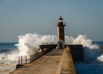 lighthouse with a big wave of water from the ocean with blu sky