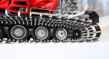 Preparation of slopes of the mountain resort before the winter season. Ratrak rolls snow on a forest track