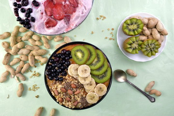 Breakfast with muesli, acai blueberry smoothie, fruits on green background. Healthy food concept. Flat lay, top vie