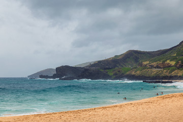 Fototapeta na wymiar Oahu beach with people swimming in big waves
