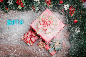 Beautiful red gift boxes bordered with pine branches red ornaments, 2019 number in middle, copy space bottom left. Snow flake fall all over