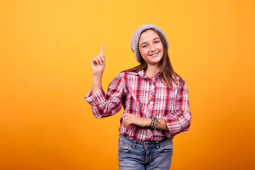 Little girl pointing in studio on yellow background. Having fun .