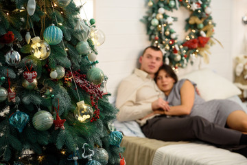 Pregnant mother and her husband at home with christmas decorations