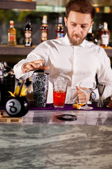 Barman in white shirt pouring drink incredient for cocktail