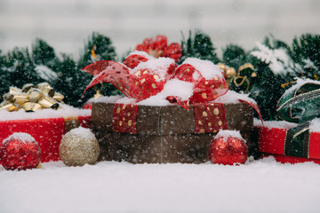 Gift boxes on snow decorarte with Christmas ornaments, snow is falling on them, feeling of greeting festival and happy winter