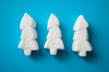 closeup of white marshmallows in shaped fir on blue background