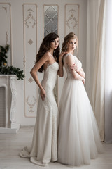 Naklejka premium Two girls models in wedding dresses. Lace Dresses. Brunette and blonde. Wedding style. Interior Studio.
