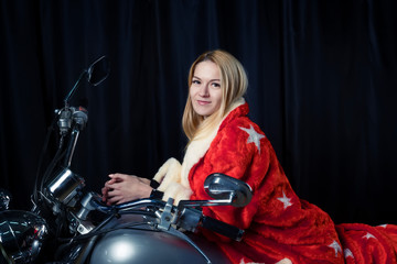 Plakat Beautiful blonde in Santa Claus outfit on a motorcycle carries gifts