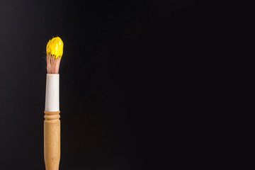 Brush in a yellow paint on a black background