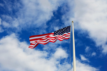 United States national flag waving in the wind against cloudy sky