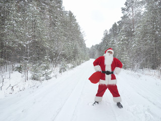 Santa Claus is walking along a snowy country road