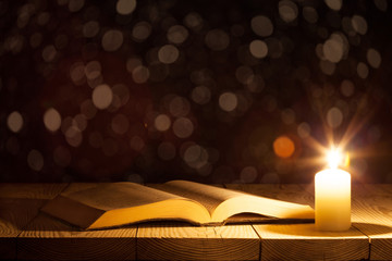 a bible on the table in the light of a candle