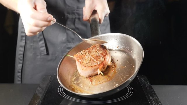 Unhealthy food concept. Close up of chef hand pouring oil on meat with spoon. Slow motion. hd