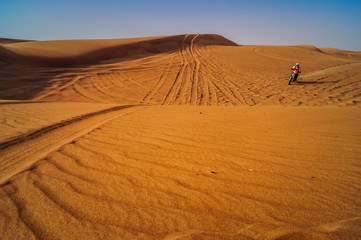 Racer on motorcycle in the desert sand dunes of Dubai.