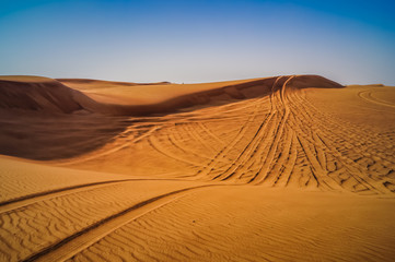 Fototapeta na wymiar Tire tracks through the desert sand dunes. Feeling lost and alone in this world.