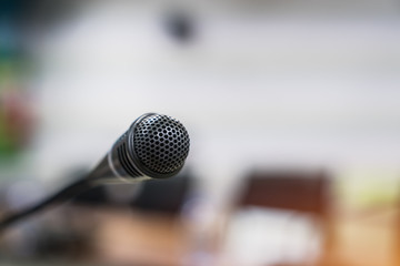 Obraz premium Mini Microphone on abstract blurred conference hall for speaker on stage in seminar room background, Business meeting and education in teaching classroom concept