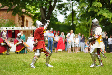 People wearing knight costumes fight during historical reenactment on annual Medieval Festival, held in Trakai Peninsular Castle.