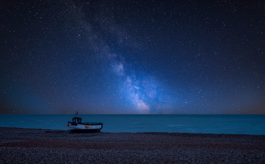 Vibrant Milky Way composite image over landscape of Abandoned derelict fishing boats on shingle beach