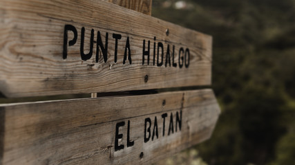 A wooden sign showing two different ways, Punta Hidalgo village or El Batan village