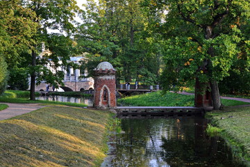 elegant old bridge with red brick turrets across the canal surrounded by forest and ground tracks...