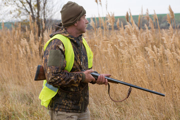 Hunter with a gun and a dog go on the first snow in the steppe, Hunting pheasant in a reflective...