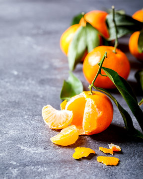 Fresh delicious mandarin, tangerine, clementine with green leaf on gray background. Ripe citrus fruits.Creative minimalistic food concept. Copy space for Text.