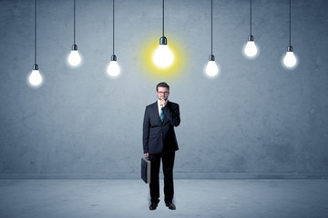 Handsome businessman in an empty space with bulbs above and uninspired face
