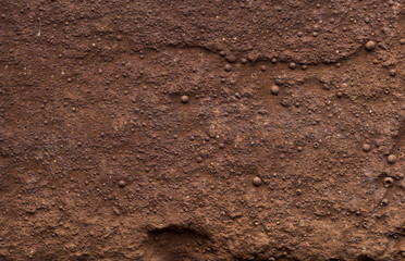 Macro shooting texture of red clay wall. Dark brown clay wall for background usage. Texture of the old tough cragged wall of brown color