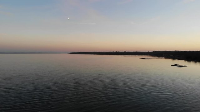Aerial view flying across the sea in Nyk&radic;&prod;bing Bugt with swimming and flying seabirds in a beautiful sunset